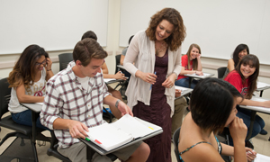 photo of classroom with instructor speaking to student at desks